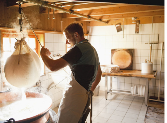 Foto eines Mannes, der Milch siebt, um daraus Käse zu machen